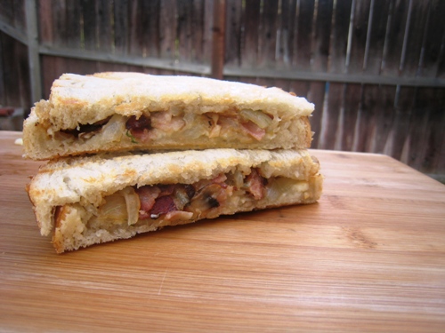 A cut in half Bacon and Brie Panini sitting on top of a wooden table