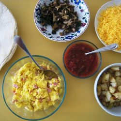 Bowls of breakfast burrito bar items laid out
