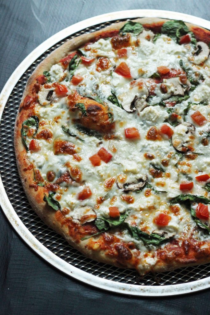 A Greek pizza sitting on top of a pan on a table