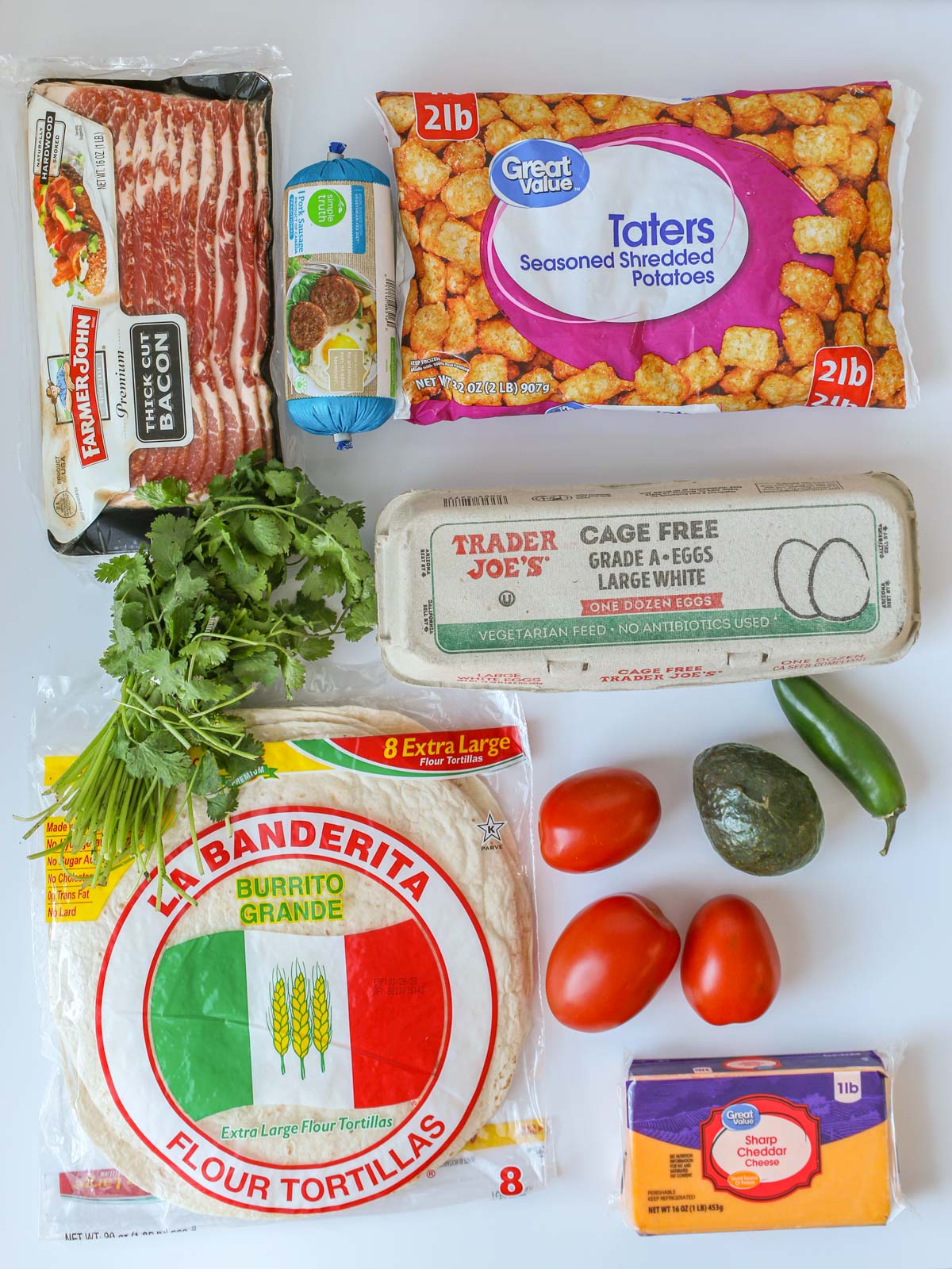 array of ingredients to make breakfast burritos laid out on white table.