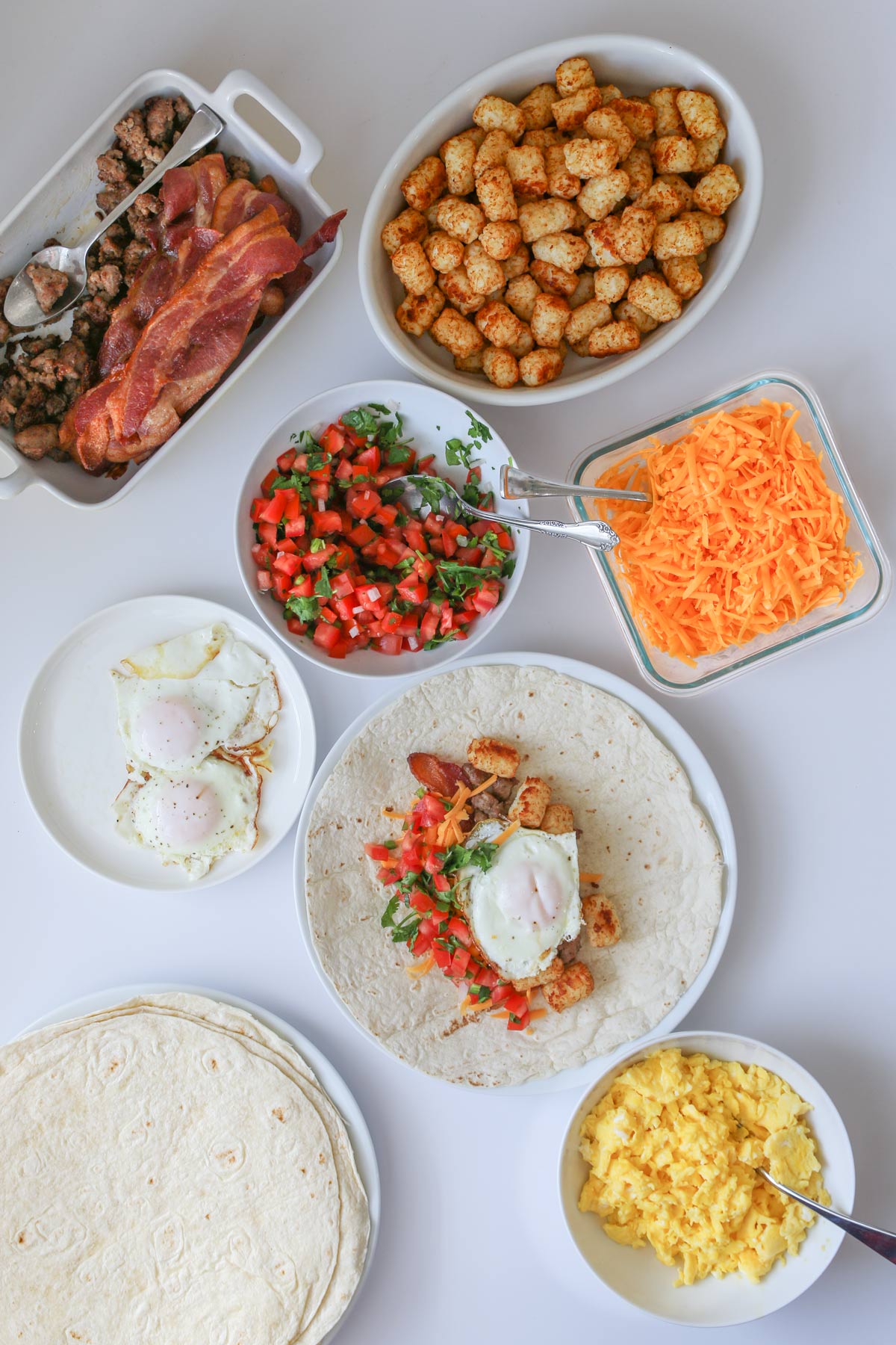 array of breakfast burrito fillings laid out on a white surface.