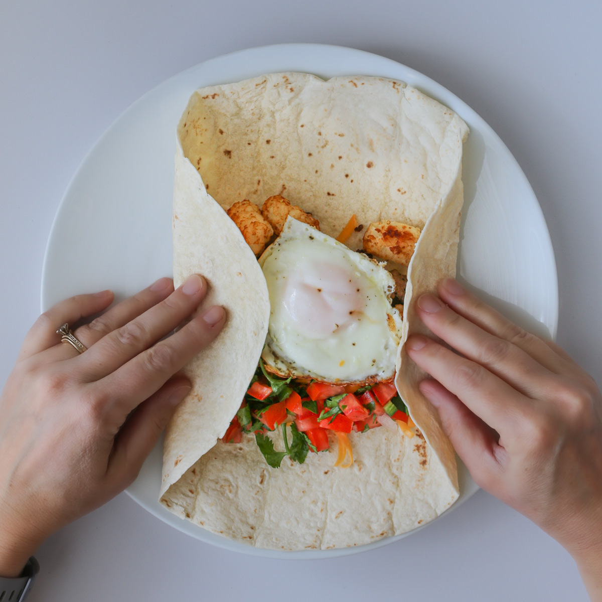 folding in sides of breakfast burrito.