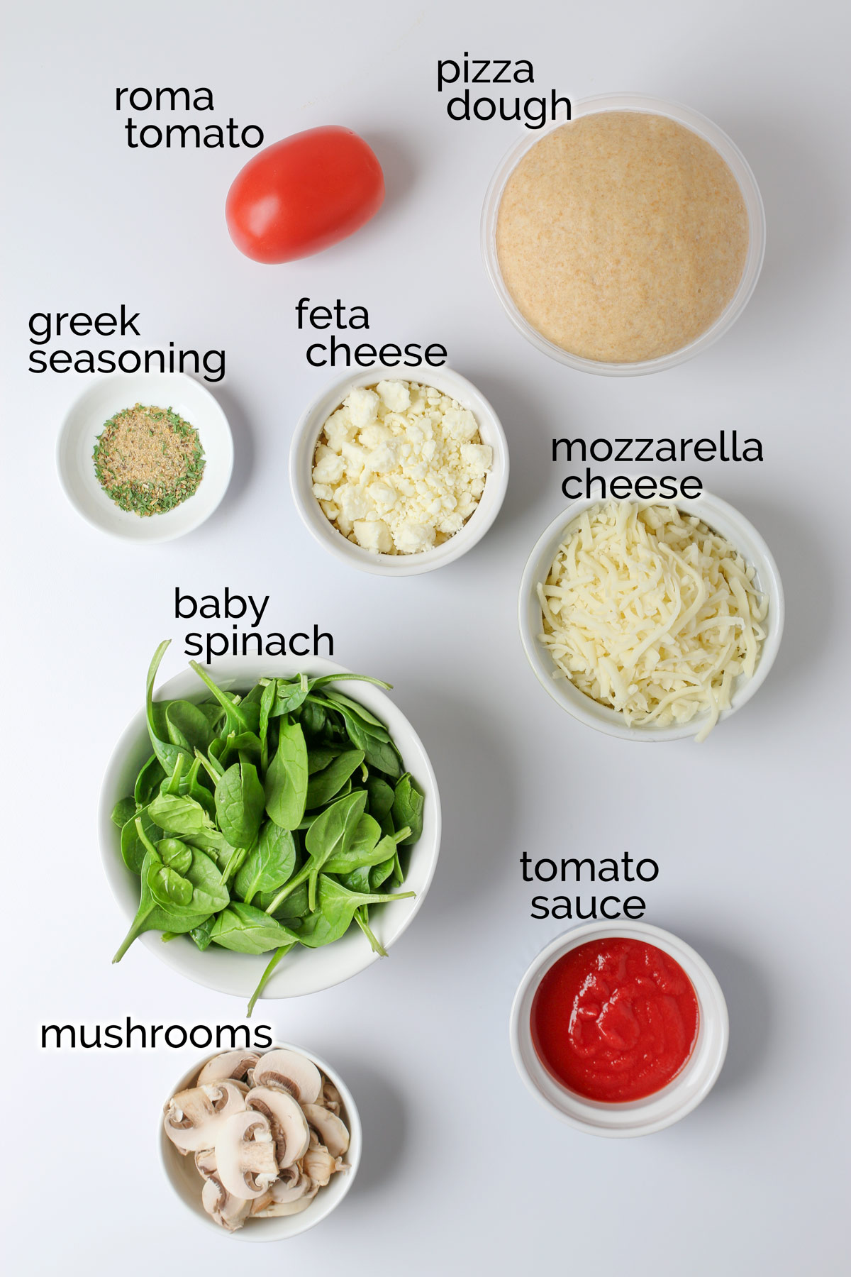 ingredients to make Greek pizza laid out on white counter.
