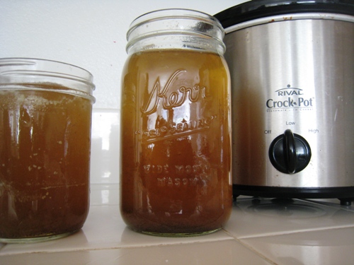 Beef broth in jars on counter, with slow cooker