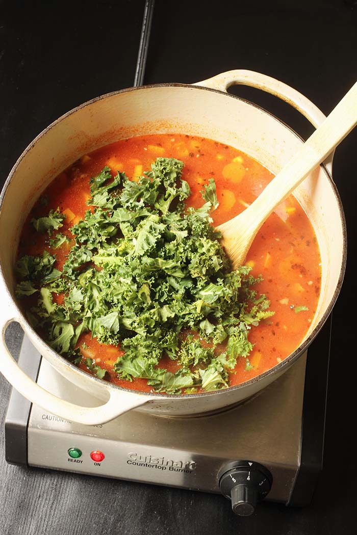 stirring kale into soup pot