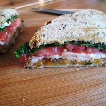 A cut in half sandwich sitting on top of a wooden cutting board