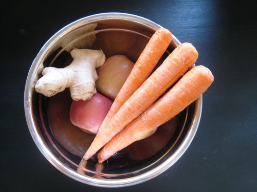 A bowl of carrots, apples, and ginger for juicing