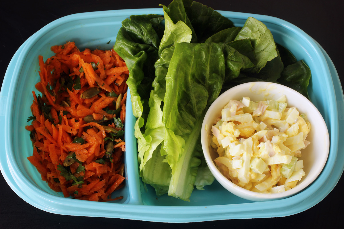 meal prep with carrot salad, lettuce leaves, and dish of egg salad