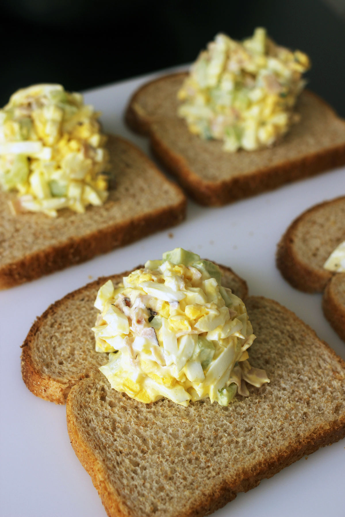 mounds of egg salad on slices of bread to make sandwiches