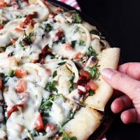 hand pulling slice of kale pizza off pan