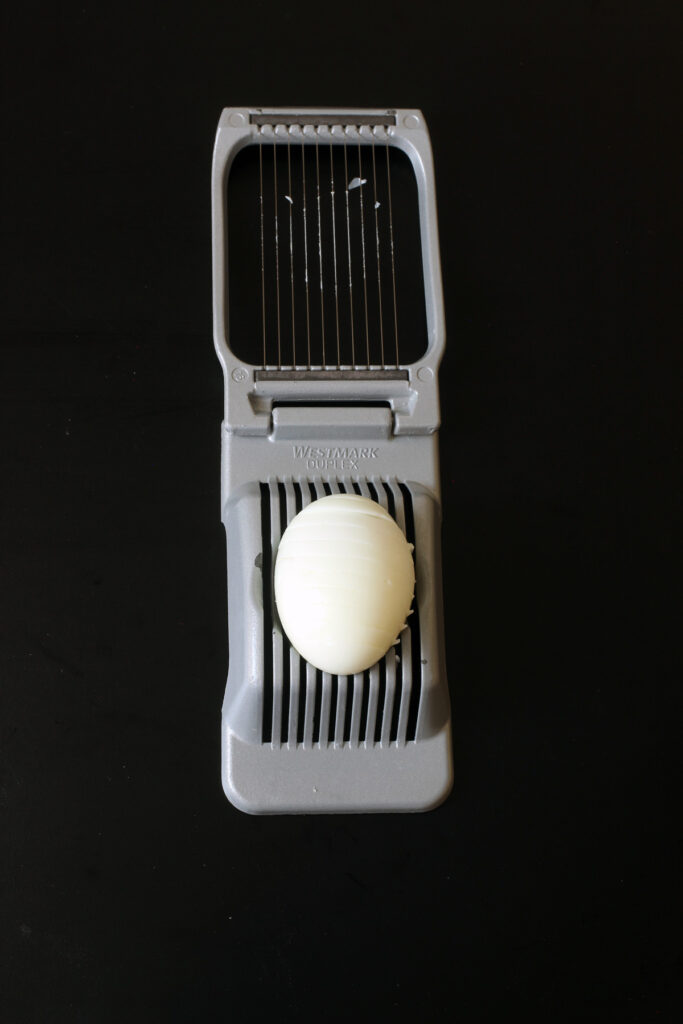 sliced egg placed vertically on slicer
