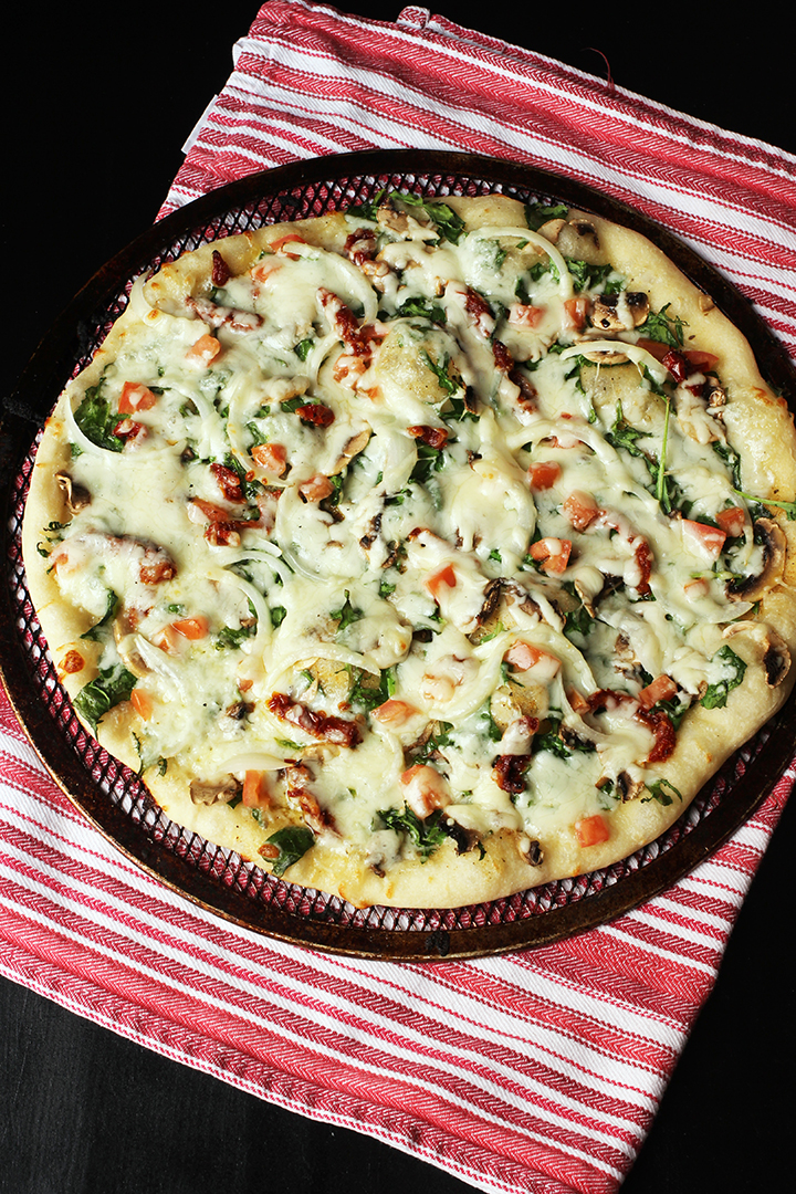 mushroom kale pizza on pan on red striped cloth