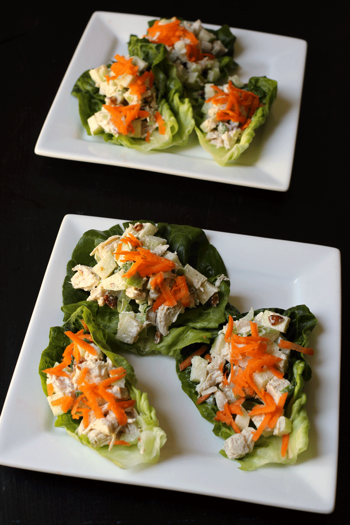 two plates with lettuce leaves piled with chicken salad
