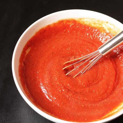 white bowl of pizza sauce with whisk