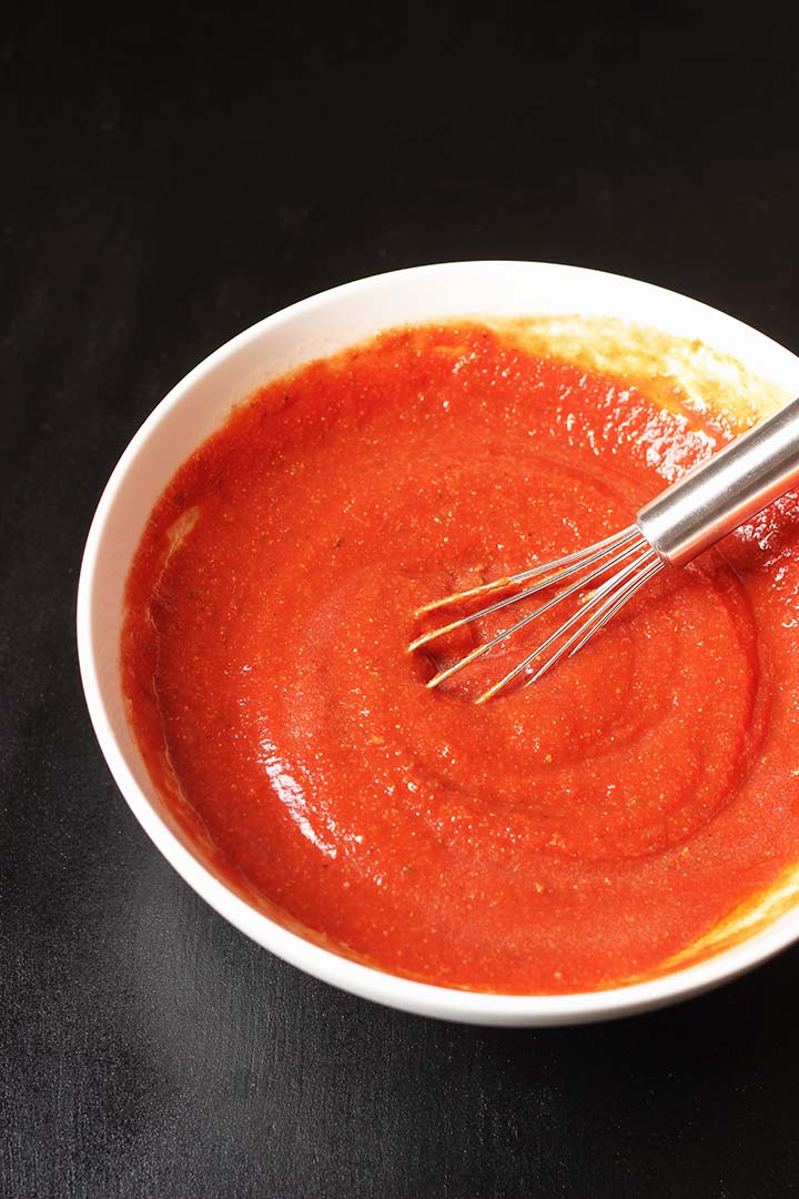 white bowl of pizza sauce with whisk