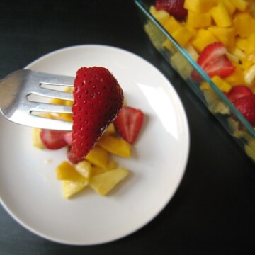 A bowl of fruit on a plate, with Mango and Pineapple