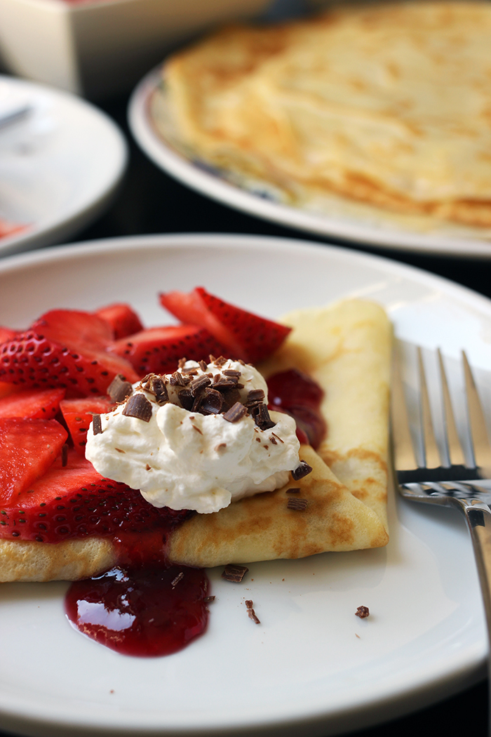 close up of crepe folded and topped with strawberries and cream