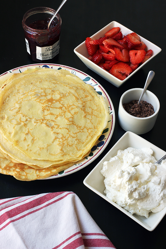 platter of crepes on table with dessert fillings.