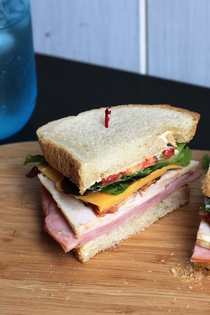 Club Sandwich coupé en deux sur une planche de bois