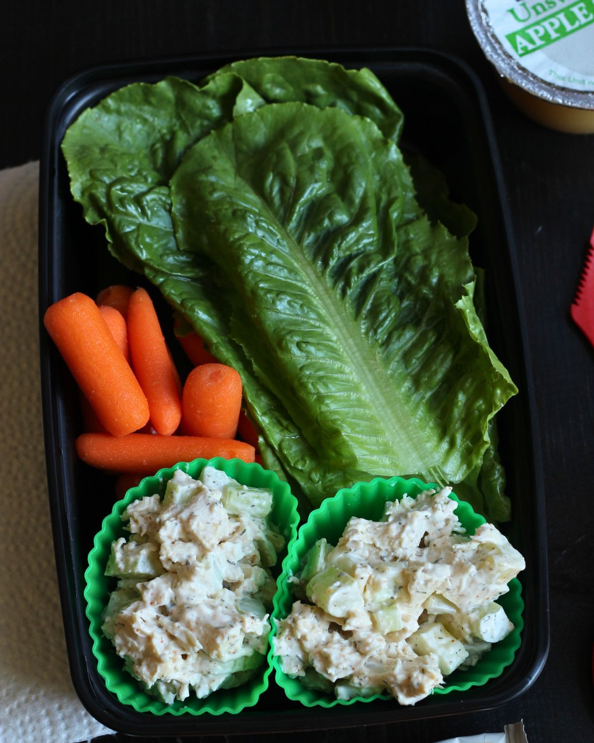 meal prep box with cups of chicken salad, lettuce leaves, and baby carrots.