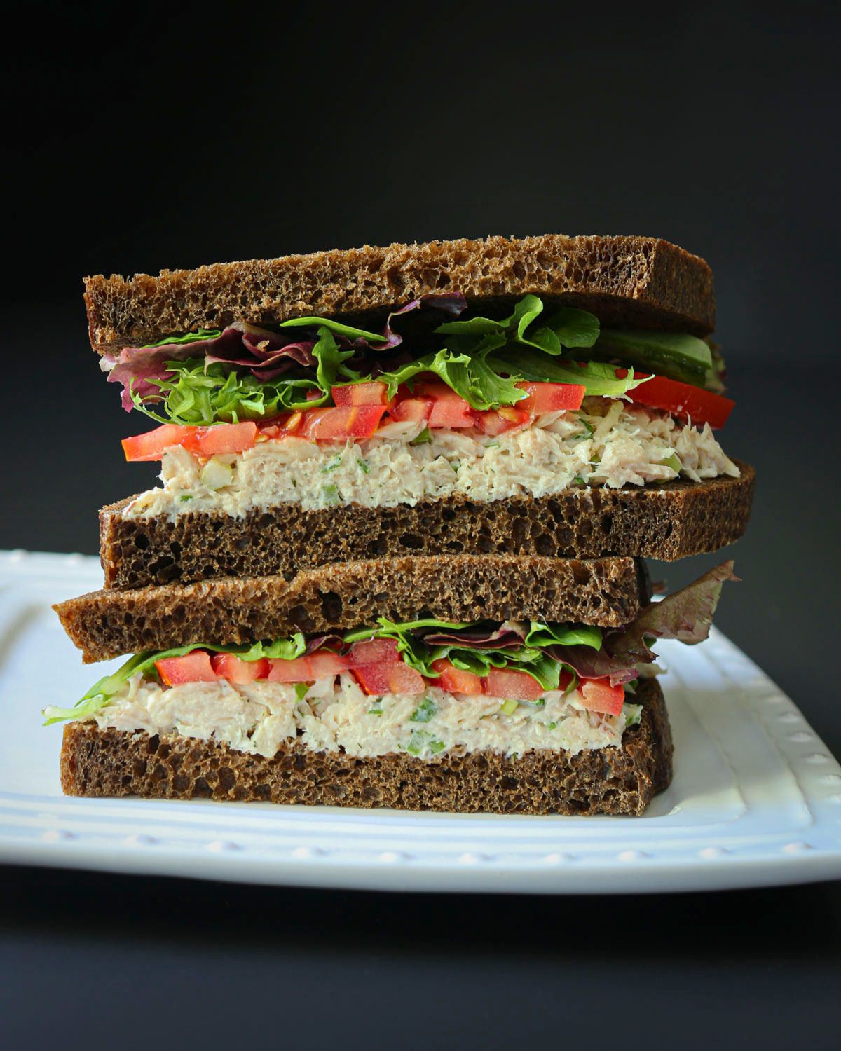 tuna salad sandwiches stacked on a plate.