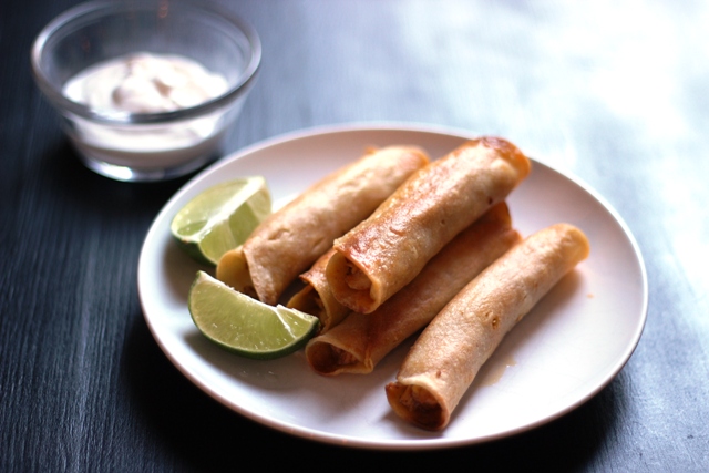 A plate of chicken flautas and lime wedges