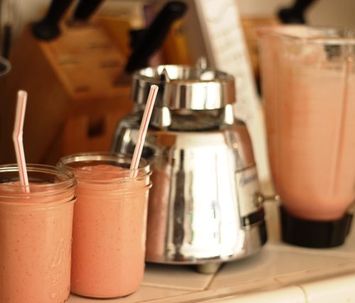 jars of smoothie next to blender on counter