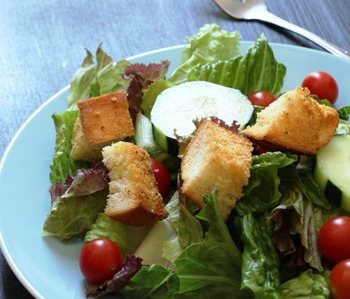 A plate of salad with croutons