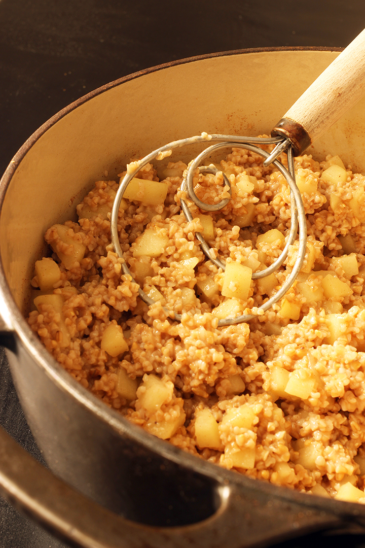 pot of cooked oatmeal with dough whisk