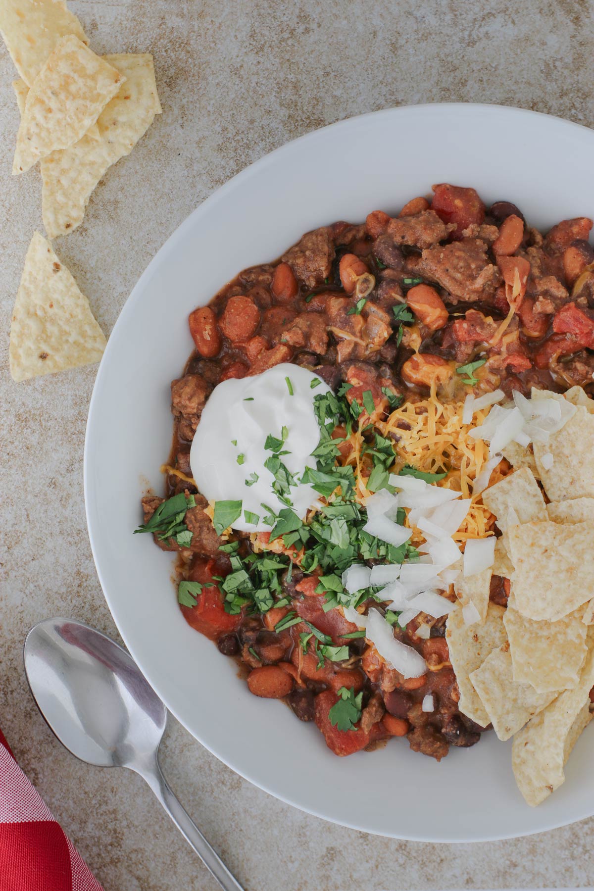 overhead shot of bowl of chili with chips and toppings.