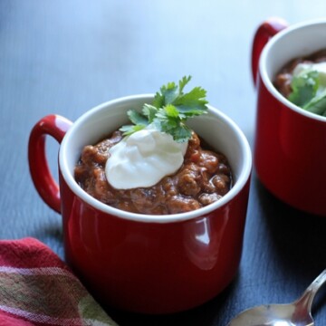 mugs of chili with sour cream and cilantro