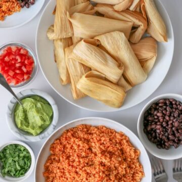 table set with bowl of vegetarian tamales, side dishes, and condiments.