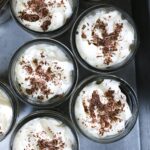 overhead shot of array of jar desserts with whipped cream and chocolate shavings.