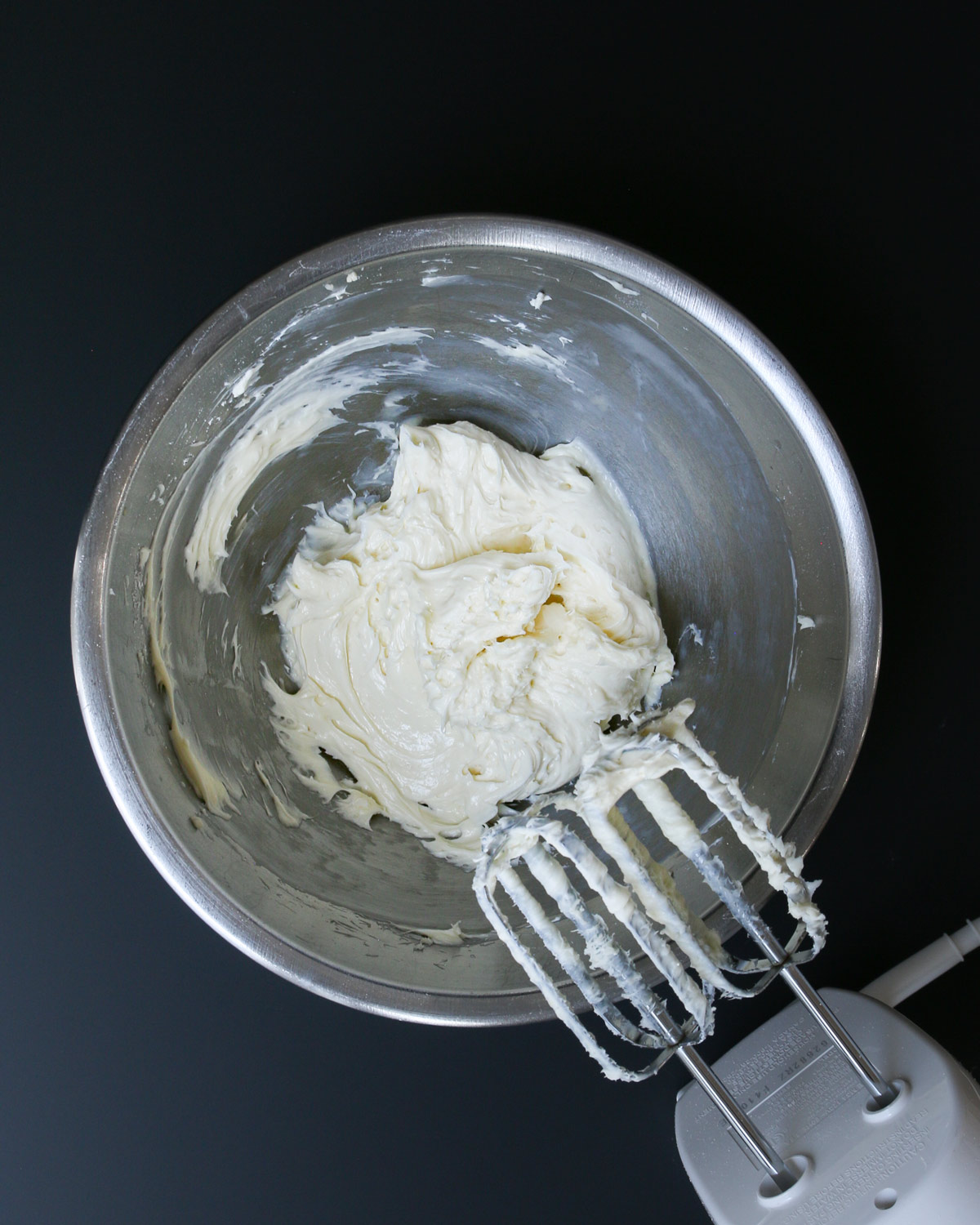 cream cheese mixture beaten with hand mixer in metal bowl.