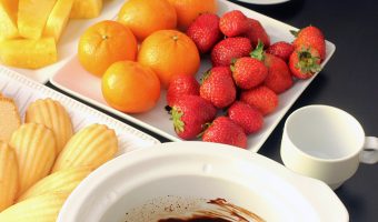 slow cooker crock full of chocolate fondue with plates of fruit and cake