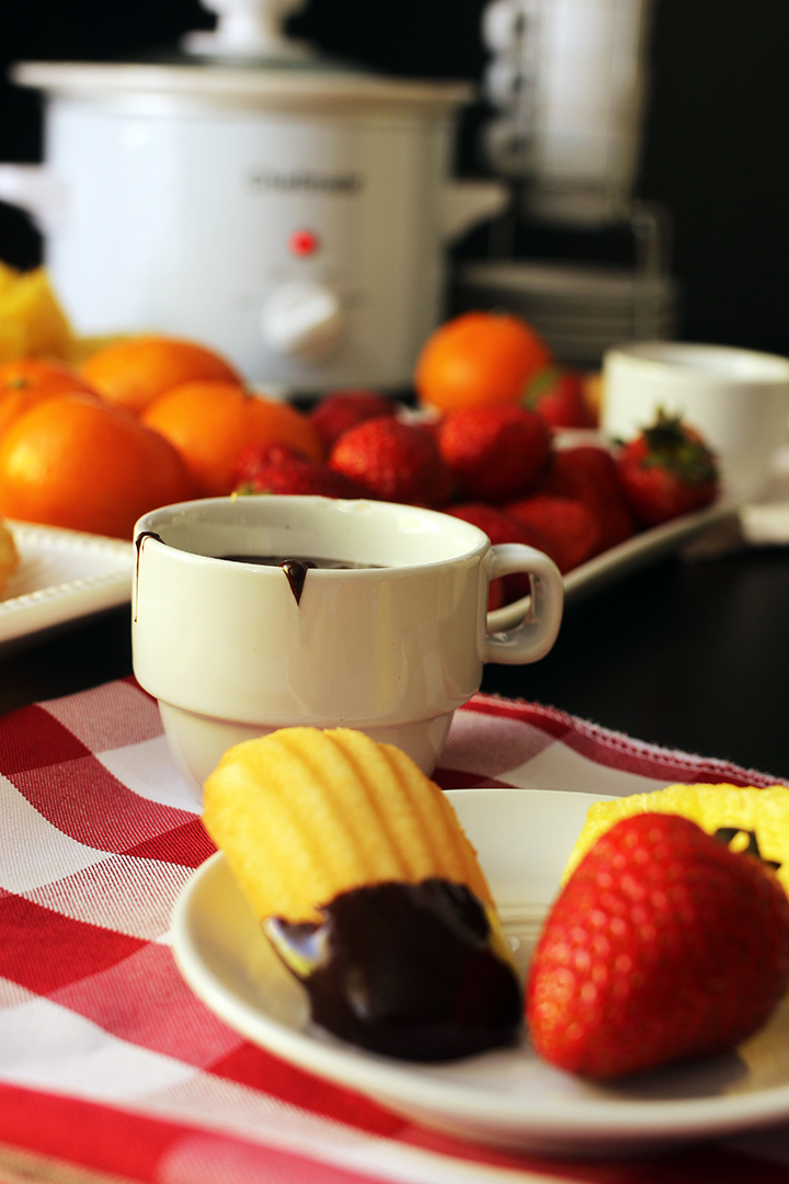 slow cooker on table with fruit and cup of chocolate fondue