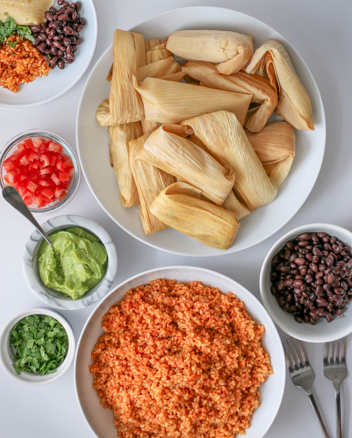 table set with bowl of vegetarian tamales, side dishes, and condiments.