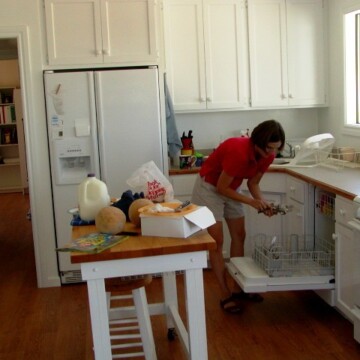 A woman reaching into dishwasher