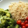 A plate rice and broccoli, with tomatoes