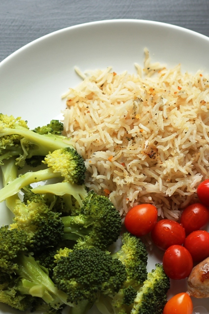 A plate rice and broccoli, with tomatoes