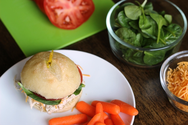 Sandwich made on a Italian Sandwich roll on a plate with carrot sticks