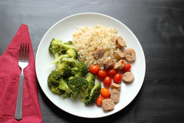 Lemon and Herb Rice Pilaf on a plate with broccoli, tomatoes, and sausage
