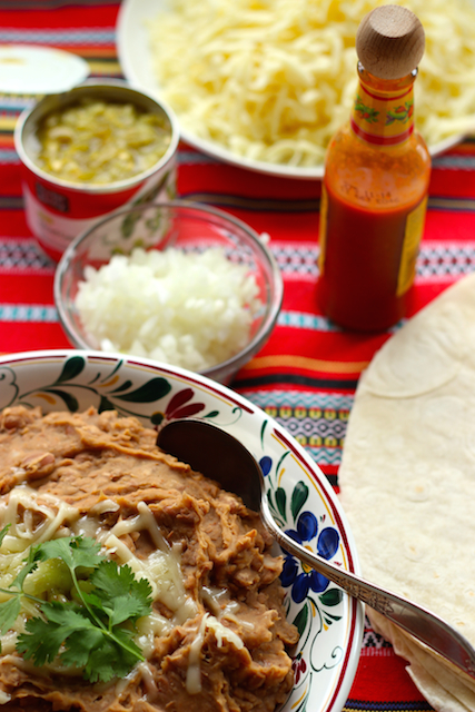 Plates of food on a table, with Burritos and Refried beans