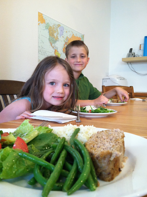 A boy and a little girl sitting at a table with a plate of Meatloaf