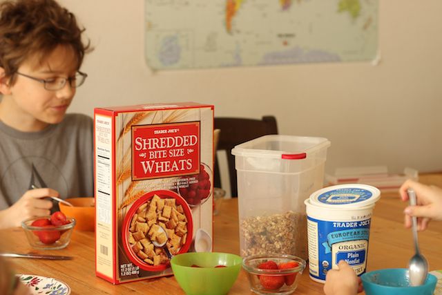 A person sitting at a breakfast table with yogurt and cereal