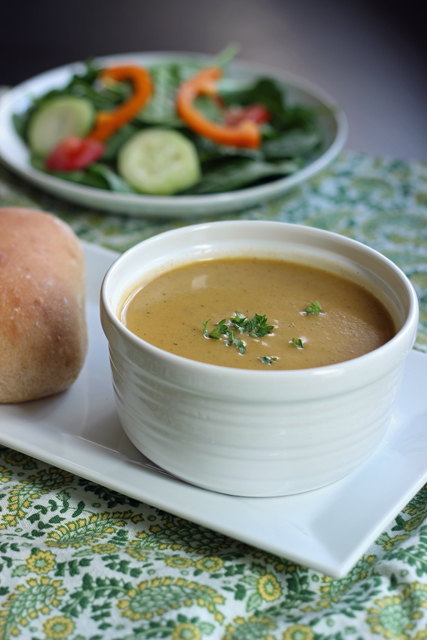 A bowl of soup on a table, with salad