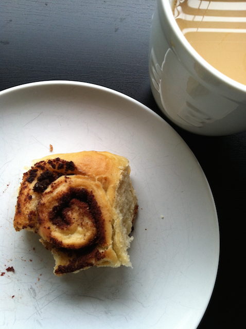 cinnamon roll on plate with cup of coffee