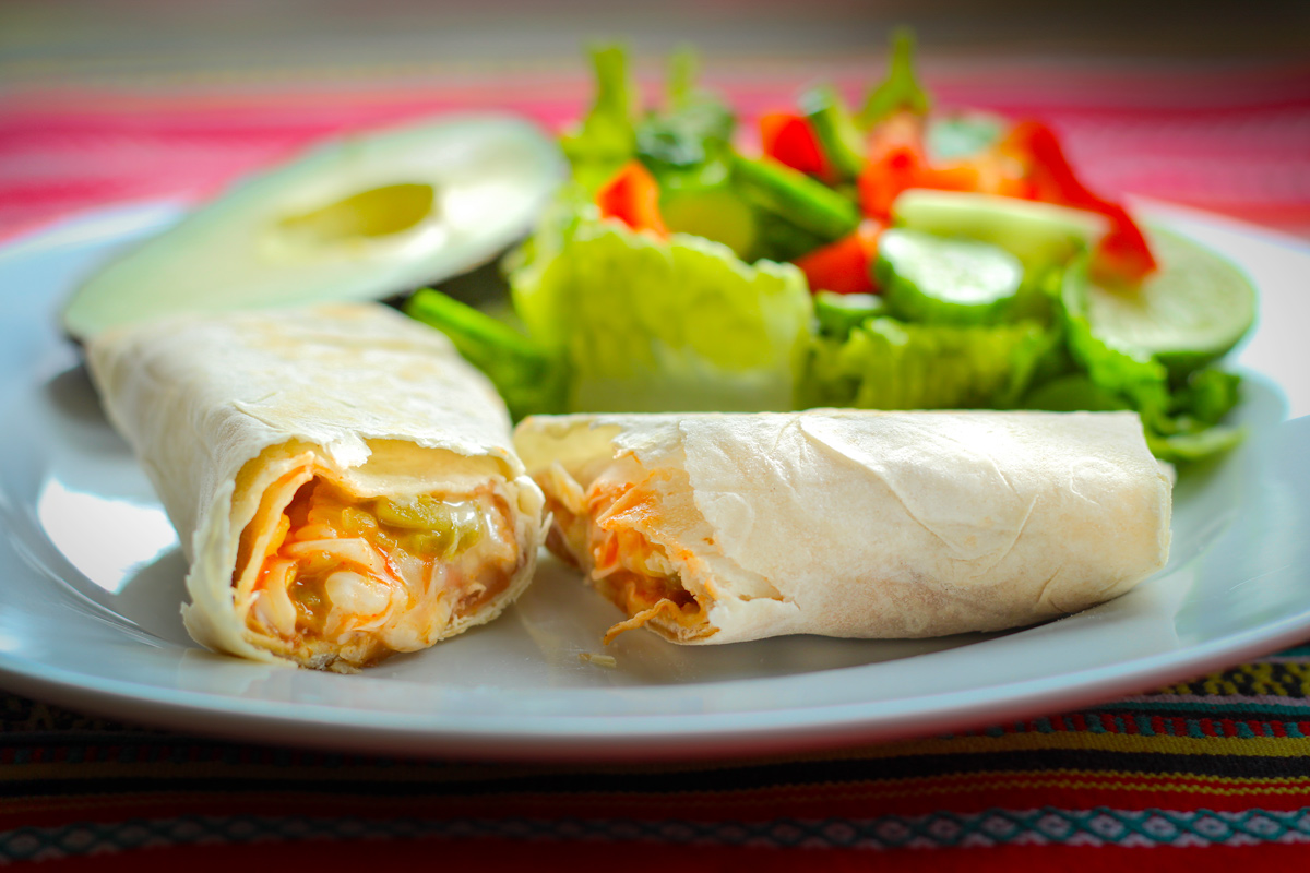 plate of salad, burrito, and avocado.