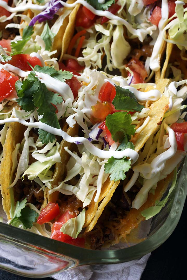 close up of tacos in pyrex pan with toppings