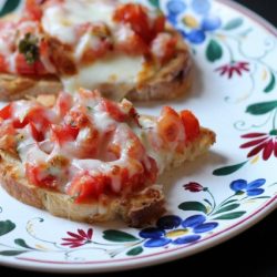 broiled bruschetta on a plate with a bite missing